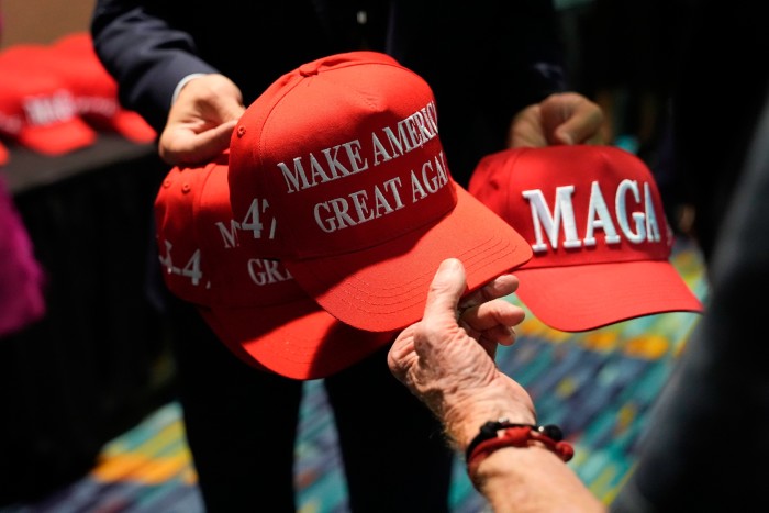 Campaign staff hand out hats before Trump arrives to speak at Palm Beach Convention Center on Tuesday evening