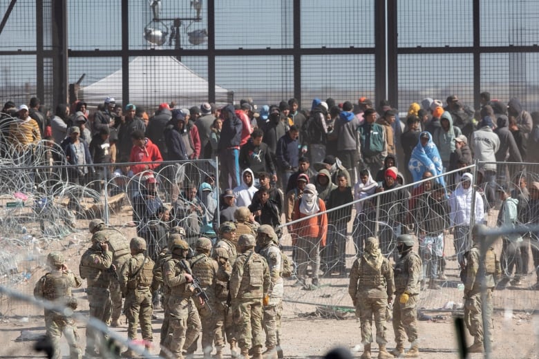 Texas National Guard watch migrants after beaching barriers set up on the Rio Grande in El Paso, Texas, March 21, 2024. A Texas grand jury on Tuesday, April 23, indicted more than 140 migrants on misdemeanor rioting charges over an alleged mass attempt to breach the U.S.-Mexico border, a day after a judge threw out the cases. 