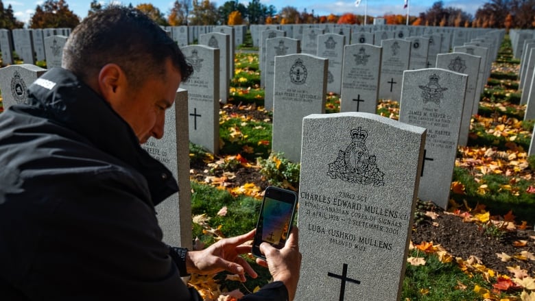 Ryan Mullens using his company Memory Anchor's app to see the history of his grandfather Charles Edward Mullens at his gravestone at Beechwood Cemetary in Ottawa. 