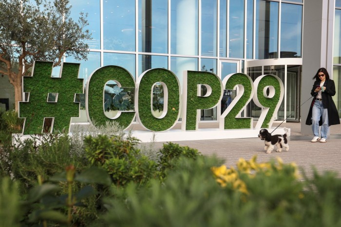 A woman walks past a sign of the COP29 United Nations Climate Change Conference, in Baku, Azerbaijan 