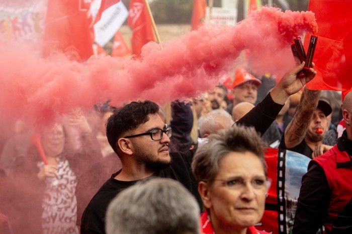 Red smoke billows as a protester holds a flare