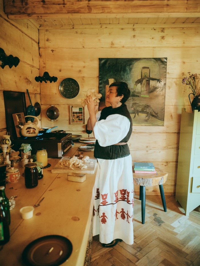 Olowska in the kitchen; on the wall hangs Luka Woźniczko’s painting The Offering, 2013