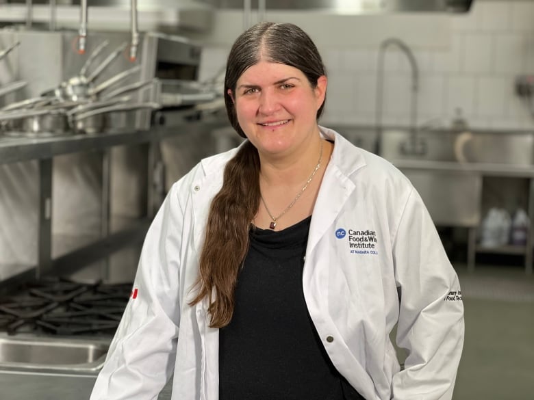 A woman in a lab coat smiles at the camera.