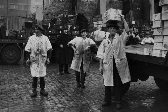 Porters at Billingsgate Market, unloading crates of fish from railway lorries before carrying them on their heads into the main market, London, circa 1945.