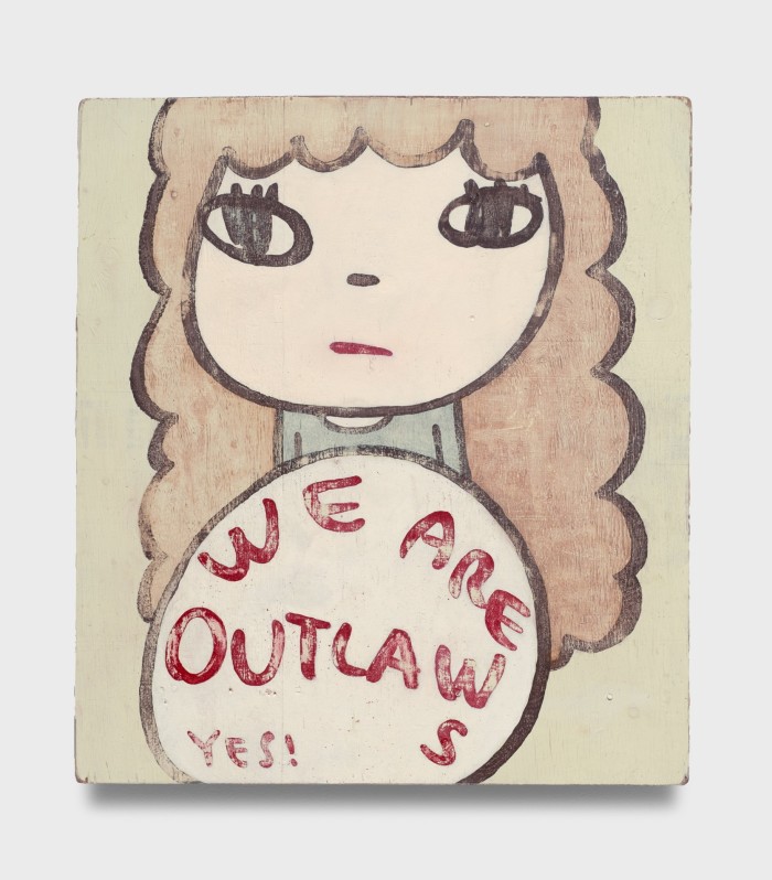 A painting depicts a simplified image of a young woman with curly hair; in front of her is a disc with the words ‘We Are Outlaws Yes!’