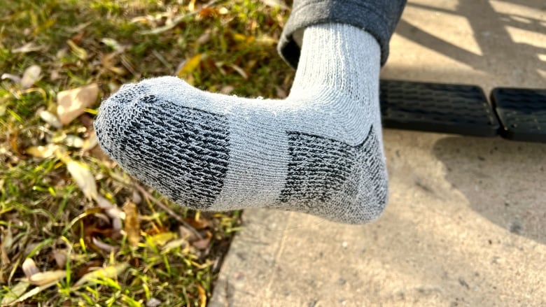 A man's right foot is pictured under a sock.