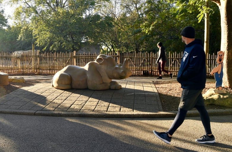 People walk past a rhinoceros exhibit at a U.S. zoo.