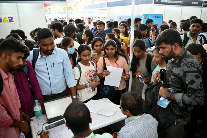 Job seekers crowd round a table at a job fair in Bengaluru