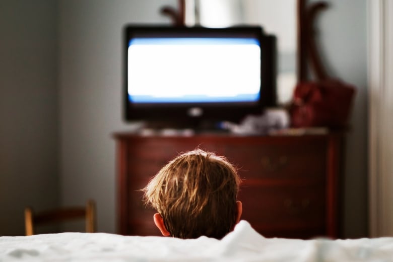 A child watching tv, from the back