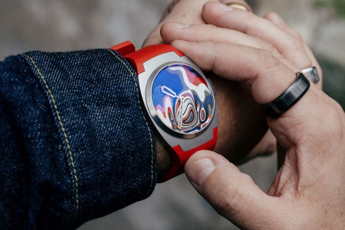 A man holding a watch with layers of multicoloured painted dials