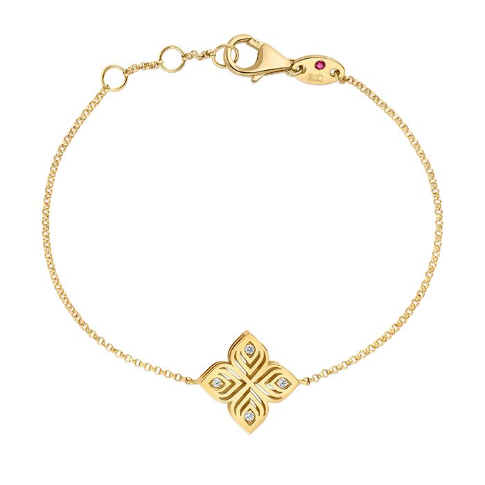 A delicate gold bracelet with a floral-shaped pendant featuring small diamond accents, and a lobster clasp with a small red gemstone detail