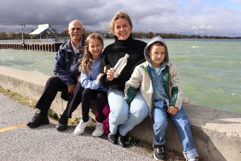 Makenzie Van Eyk holds the message in a bottle she threw into Lake St. Clair 26 years ago. She's sitting with her teacher from that time and her two kids. They're in the area where she sent the plastic bottle into the water and where it was found. 