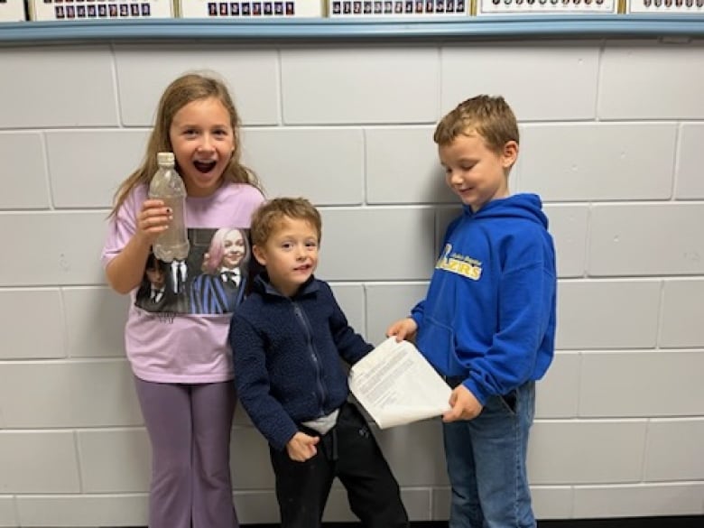 Kindergarten student River Vandenberg, middle, recently found the letter in a bottle near the shore of Lake St. Clair. Scarlet Van Eyk, left, is in grade 4, the same grade that her was in when she wrote the letter. On the right is Scarlet's brother, Huxley.