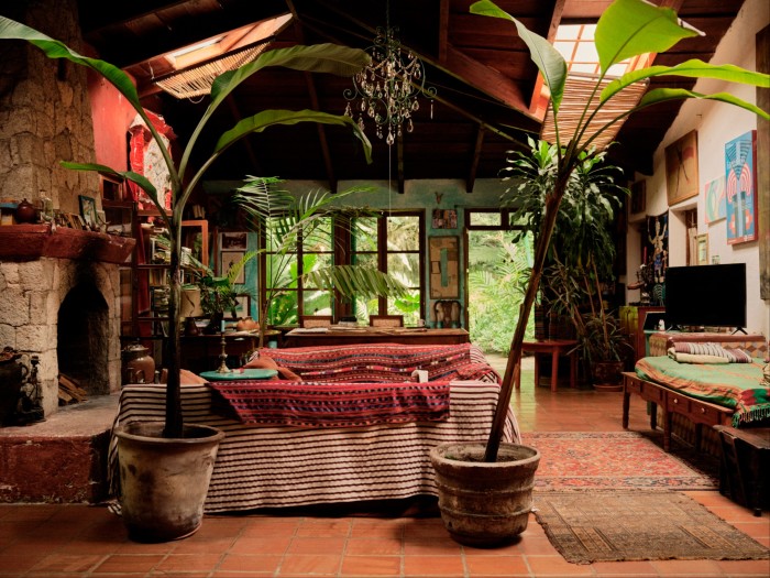 A rustic interior filled with lush greenery and vibrant textiles, evoking a tropical, bohemian ambiance