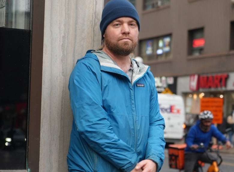 A man stands in front of a busy street.