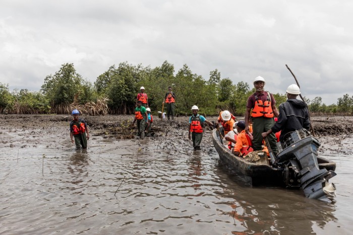 People in hi-vis vests and hard hats stand and sit on a boat