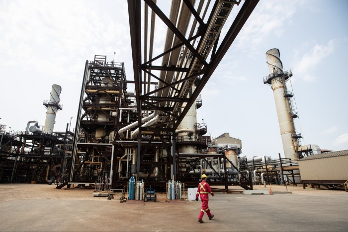 A worker walks beneath a large  network of pipes