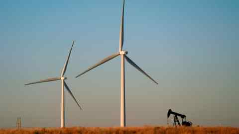 Wind turbines on a field with an oil pumpjack behind them