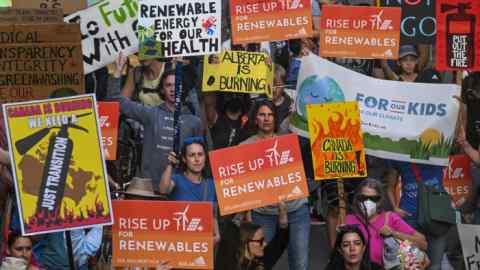 The crowds hold up protest banners