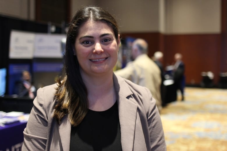 A woman in a black top and brown suit is pictured in a conference ballroom in Calgary.