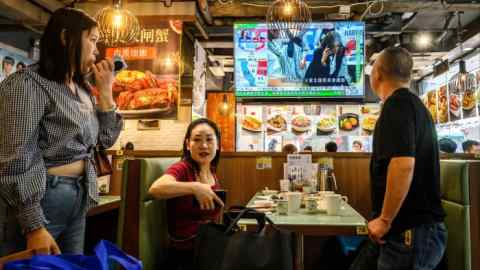 People look at the preliminary results from the US election on a TV screen at a restaurant in Hong Kong