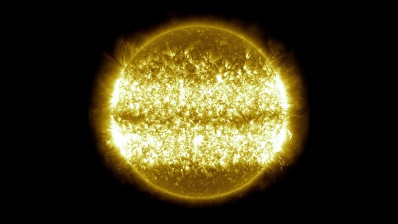 A brilliant golden sun looks fuzzy as it shows an average of all the surface eruptions over ten years with two bright white bands around it about 30 degrees north of the equator and 30 degrees south of it.