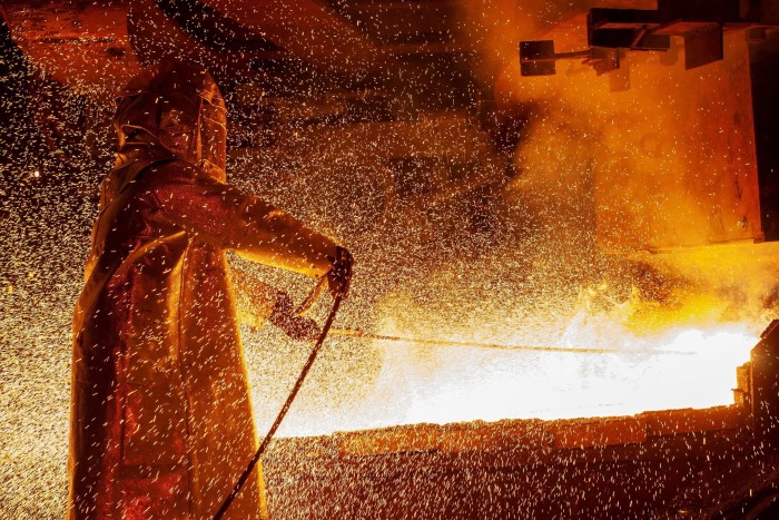 A worker in protective equipment tends a furnace amid a cloud of sparks at a nickel smelting plant in Soroako, South Sulawesi, Indonesia