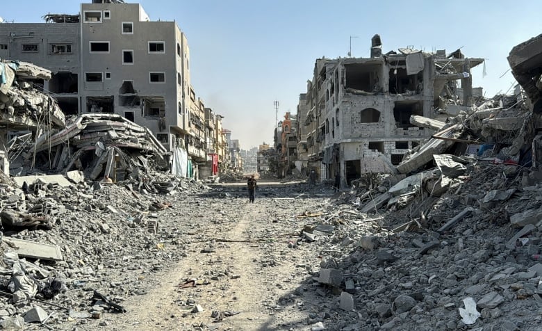 A person walks through rubble.