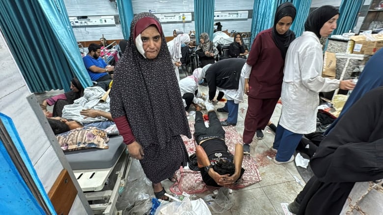 Dozens of people lie on a hospital floor.