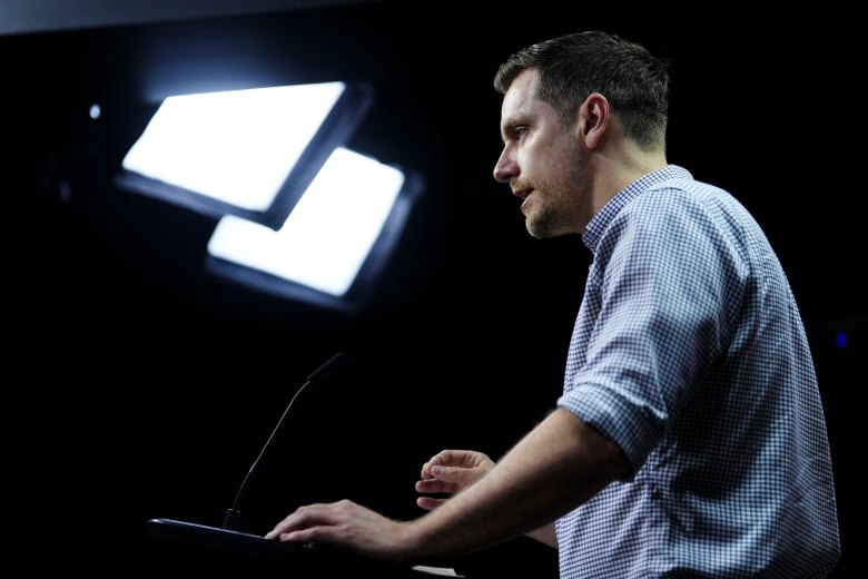 A union leader under television lights at a news conference.