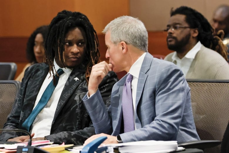 A man talks with his lawyer inside a courtroom.