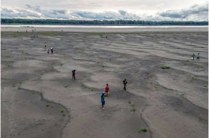 Yagua Indigenous people carry water and other goods due to the low level of the Amazon river at Isla de los Micos in Colombia