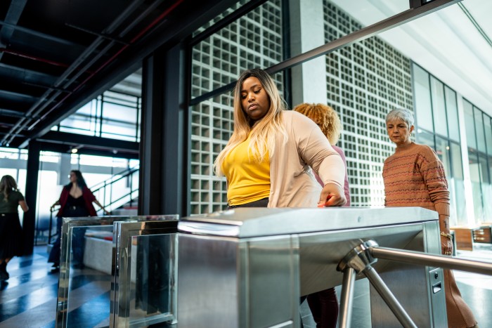 A woman entering a building through a turnstile