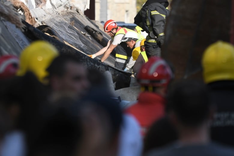 Rescue workers search for victims in the aftermath of an outdoor roof collapse.