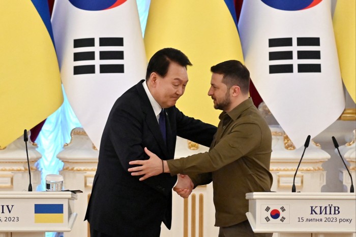 Yoon Suk Yeol and Volodymyr Zelenskyy shake hands in front of Ukrainian and South Korean flags after making their statements following talks in Kyiv on July 15 2023