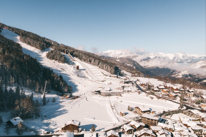 Snow covered mountain, skiers and resort buildings in the valley below