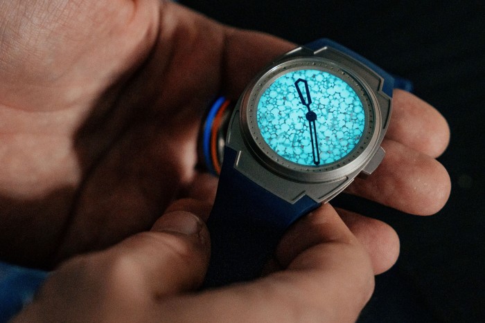 A man holding a glowing blue Arcanaut watch