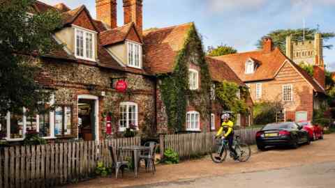 A cyclist outside the Post Office and shop in the historical picturesque Chilterns village of Hambleden