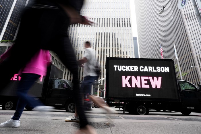 A mobile billboard with the words ‘Tucker Carlson knew’ drives past the Fox building